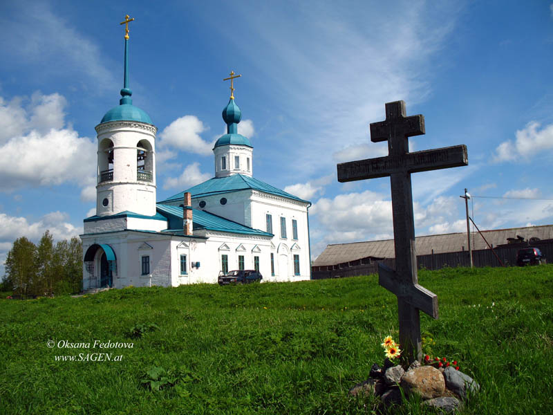 Das Gedenkkreuz „an alle unschuldig Ermordeten“ und die Entschlafung-der-Gottesgebärerin-Kirche © Oksana Fedotova